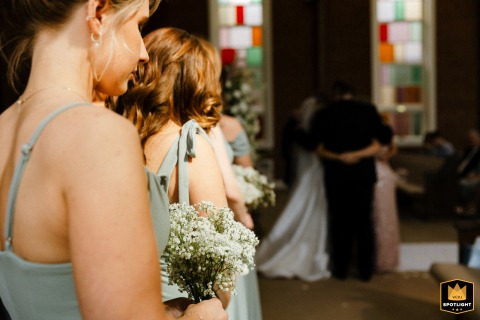Families bow heads and pray together during the wedding ceremony inside a Virginia church, creating a moment of solemn unity.