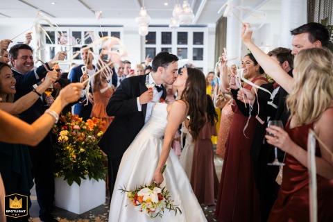 Bride and groom kiss amid falling confetti, surrounded by cheering guests, celebrating their wedding at Hotel Mediterraneo Sorrento, Italy.