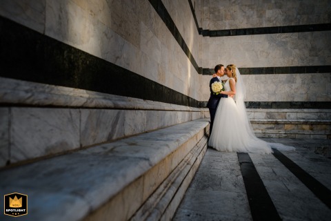 At the Duomo di Siena in Tuscany, a couple's portrait is captured in striking black and white, with graphic leading lines of the cathedral’s architecture drawing the eye toward their intimate connection.