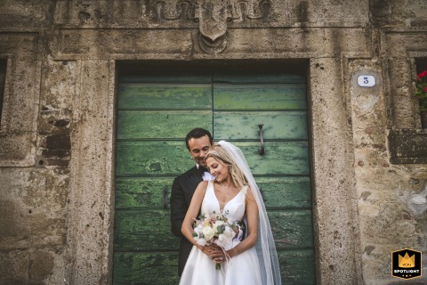 At Rocca di Cetona in Tuscany, the couple poses for a romantic portrait framed by an old-world stone-carved doorway, blending timeless elegance with the charm of historic architecture.