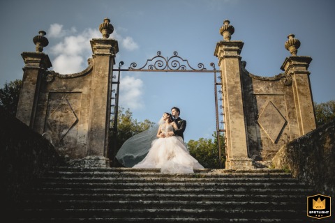 At Castello di Celsa in Tuscany, the couple poses for a timeless portrait, beautifully framed by the old-world stone-carved entrance and grand staircase, capturing elegance and romance in a historic setting.