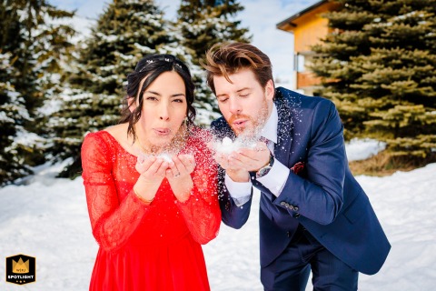 At Les 2 Alpes ski station in France, the couple playfully blows snow from their hands toward the camera, creating a lively, snappy photo bursting with bright colors and joyful winter energy.