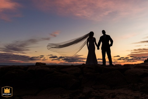 At The Wharf in Falmouth, bold silhouettes and a flowing veil stand out against a glowing sky, blending romance and drama in this unforgettable wedding scene.