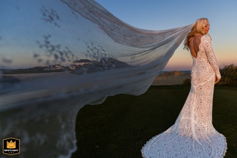 At The Club at New Seabury, golden hour light bathes the bride in a warm glow as her flowing lace gown creates a striking and elegant portrait.