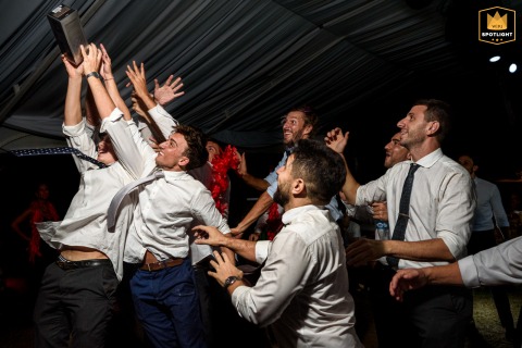 In Rosario, Santa Fe, the groom’s friends eagerly reach and compete to catch the bottle he has just tossed, filling the scene with laughter and energetic excitement at the celebration.