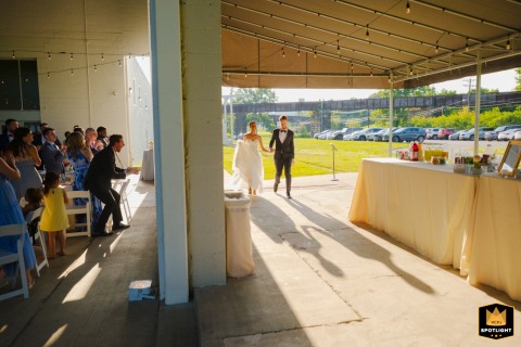 At The Gem in Pittsburgh, PA, the newlyweds make a joyful entrance at their wedding reception, beaming with excitement as family and friends cheer them on.