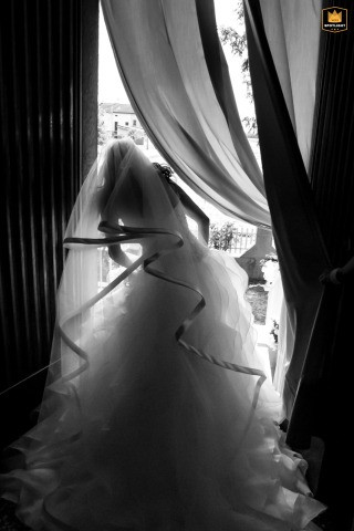 At the bride’s home in Mantua, Italy, a black and white silhouette is captured from behind as she stands by the window. 