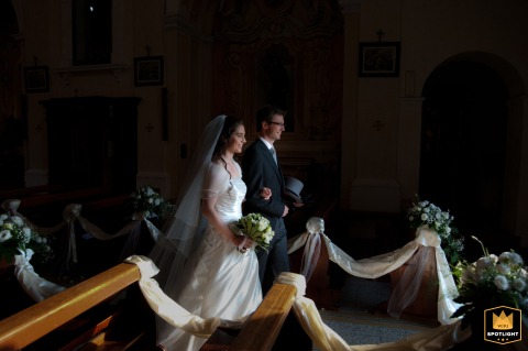 Outside Santissima Trinità in Ceresara, Mantova, Italy, the couple’s exit, framed by stunning floral arrangements. Bathed in light from the church’s main doorway, the radiant moment beautifully highlights their joy.