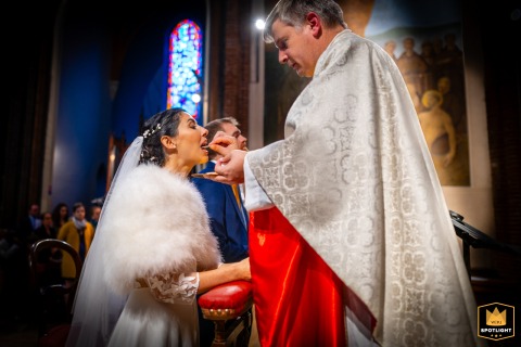 Inside a church in Toulouse, a quiet moment of communion unfolds during a wedding ceremony. The intimate atmosphere, filled with reverence and hope, highlights the couple’s spiritual connection as they share this meaningful ritual.