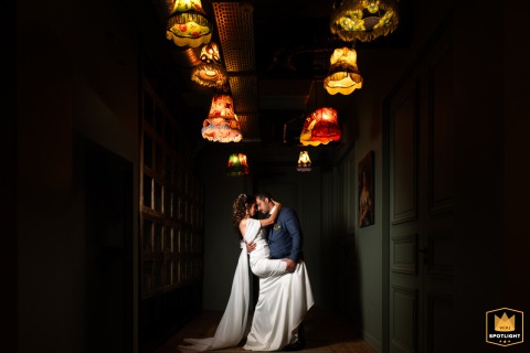 In Auvergne, a couple's portrait is captured under a light fixture. The intimate lighting highlights their connection, creating a warm and focused image.