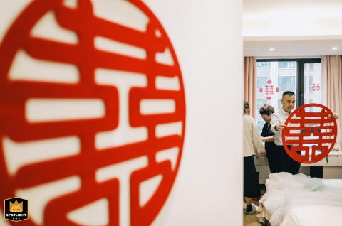 In Kaifeng, China, a father decorates a room with traditional Chinese "double happiness" characters. He prepares the space for the wedding celebration.