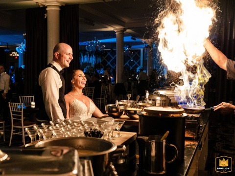 A chef's fiery expertise draws a stunning reaction from the couple at their Cescaphe wedding in Philadelphia. The burst of flames creates a memorable moment.