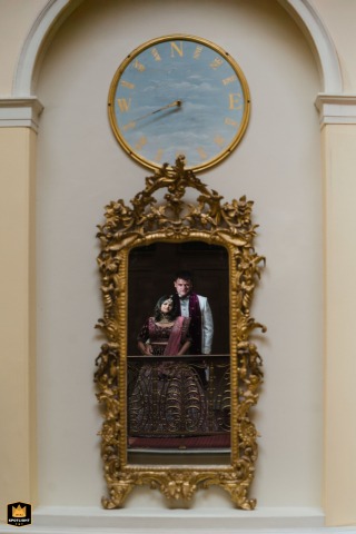 A couple's portrait is captured in a mirror at an ornate reception venue in England. The reflection highlights the elegance of both the couple and the fancy indoor setting.