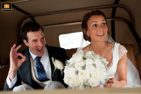 Leaving the church in Wheathampstead, Hertfordshire, the groom gives an "OK" sign to guests alongside his new wife. The celebratory gesture captures a moment of joy.