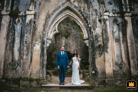 In Sintra, Portugal, a couple poses in the entrance of a ruined church. The dramatic backdrop of the historic ruins creates a striking and romantic portrait.