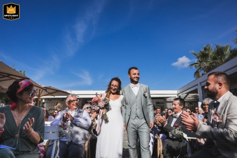 The bride and groom walk down the aisle at Restaurant La Beach House in Anglet, France. This marks the beginning of their secular ceremony with the beautiful venue as their backdrop.
