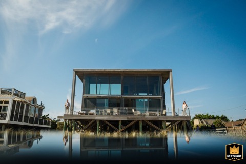 On Fire Island, New York, the photographer cleverly uses a phone’s reflective surface to capture the beach house. Appearing tiny, the bride and groom stand on either side, creating a whimsical, creative portrait filled with charm and imagination.
