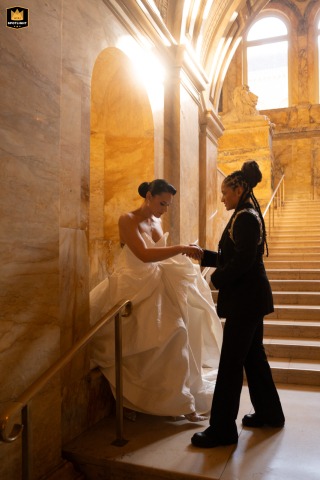 A couple poses for a wedding portrait on a stair landing at the Boston Public Library. The library's ornate architecture creates a beautiful and dramatic backdrop for the indoor session.