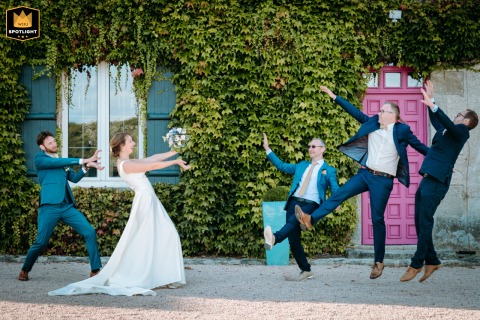 A group poses for a fun "Kamehameha" themed photo at the Château du Mouchetard. The energetic shot is taken in front of an ivy wall and a building with colorful paint.
