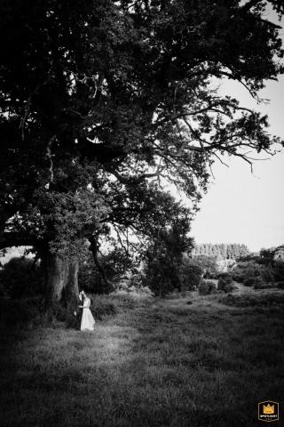 Under a large oak tree at Château du Mouchetard, a couple is captured in a portrait. They share a quiet photo session, their connection highlighted by the natural backdrop of the French venue.