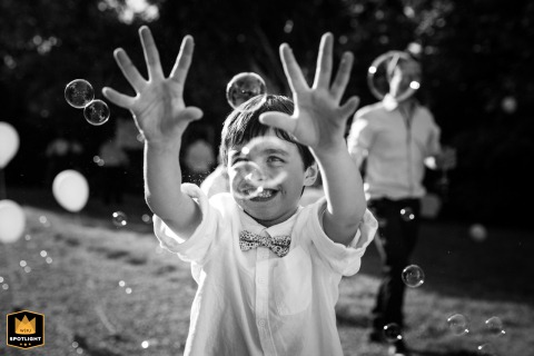 In a black-and-white photo at Domaine En Naudet in Tarn. The child playfully tries to catch bubbles, creating a joyous and timeless wedding portrait.