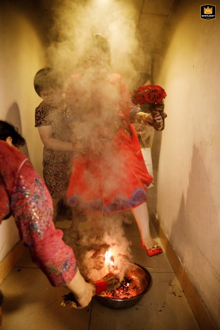 During a traditional wedding custom in Shenzhen, China, a bride steps over a smoking fire pit. This act is believed to ward off evil and bring good fortune to the newlyweds.