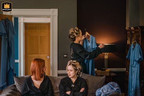 At Grassfield Hall in Harrogate, Yorkshire, UK, bridesmaids prepare for the wedding, surrounded by their elegant dresses. The candid scene captures joy, excitement, and friendship during this special getting ready moment.