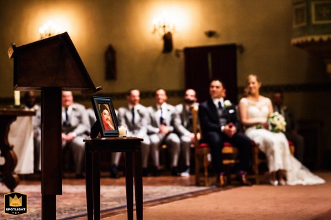 Wedding day details are the focus of a photograph at Mission Santa Clara de Asís. The couple is visible, out of focus, in the background, creating a sense of intimacy and atmosphere during the ceremony.