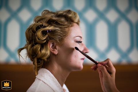 A bride at the Dream Inn in Santa Cruz, California, has her makeup applied by an artist. Captured in profile, the photo shows a quiet and focused moment of preparation before the wedding.