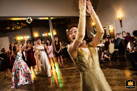 The bride, on the dance floor at The Club at Castlewood, throws her bouquet. A group of excited women jump to catch it, a fun wedding reception moment captured in Pleasanton, California.