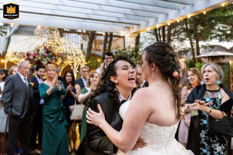 The couple share their first dance at The Gables Inn. One laughs with delight as the other looks on, creating a genuine and heartwarming image of their newlywed joy in Beach Haven.