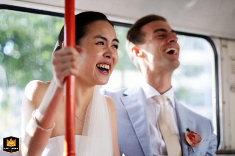 Seated on a London bus, a bride and groom share a happy, candid moment. The couple's joyful expressions and the classic bus capture the spirit of their wedding.