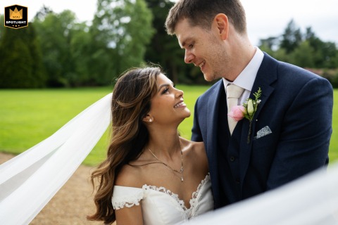 A couple poses off-center at Shendish Manor, with her veil dramatically sweeping around the frame. The punchy, vibrant colors create a dynamic and eye-catching wedding portrait.