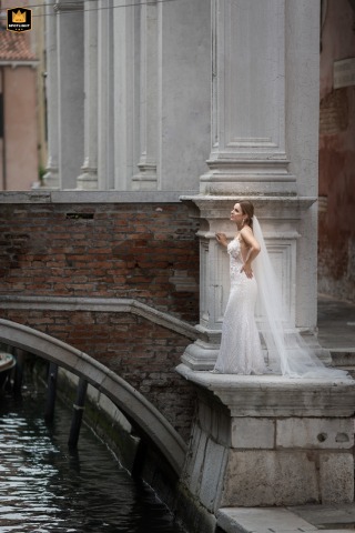 Venetian Vows: A Bride's Elegant Pose on an Old Stone Platform Bride on a stone platform of an old building in Venice, Italy, posing in a wedding dress.
