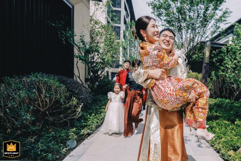 Kaifeng, China: A Groom Carrying His Bride Over the Threshold, Beginning Their Journey Home Man carrying his bride home in Kaifeng, China during their wedding.