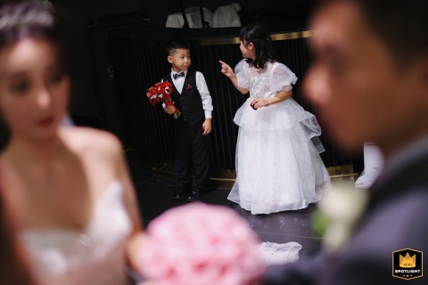 Love Blossoms: Shanghai Ring Bearer and Flower Girl Share a Sweet Moment Galleria, Shanghai, China: Ring bearer and flower girl share a moment behind the newlywed bride and groom.