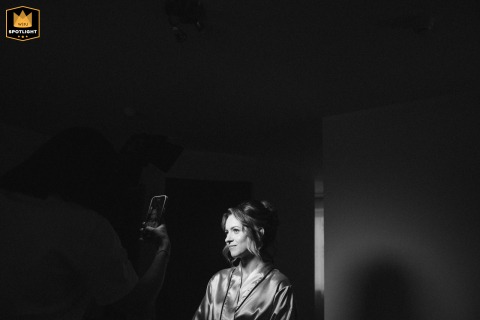 Hotel Makeup Application in Poland: A Bride's Moment in Contrasting Light Bride having makeup applied in contrasting light inside a hotel in Poland.