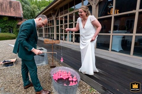 Cocktail Hour Quack-tivity: A Playful Bride and Groom's Wedding at Lille Nord: The bride and groom laugh while fishing for ducks during their cocktail party.
