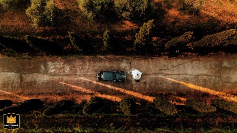 An Enchanting Sunset Drone Shot of a Couple and Their Car Wedding couple and their car at sunset, photographed by a drone in the La Valle Castelnuovo Magra driveway.