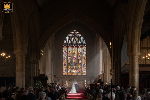 Love’s Light Shines on the Newlyweds Praying at Olney Church’s Altar Bride and groom kneel at the altar for prayers as sunbeams stream through the windows of Olney church.