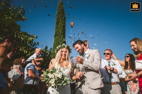 Joyful Confetti Toss Amidst Celebrating Guests at a Tuscan Wedding Ceremony Joyful confetti toss after a wedding ceremony at Castel Bigozzi in Monteriggioni, Tuscany with celebrating guests.