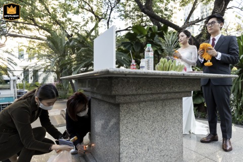 Quiet Moment of Prayer and Light at the Altar in Bangkok A wedding photojournalist captures a couple praying at an altar, while attendants use a stone altar to block the wind so they can light candles at the Plaza Athenee in Bangkok.
