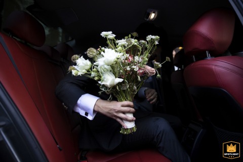 Bridal Bouquet Contrasted Against Red Leather in Bangkok's Plaza Athenee A wedding photojournalist captures a detail shot of a bouquet in a hand, contrasted against the red leather interior of a car at the Plaza Athenee in Bangkok.