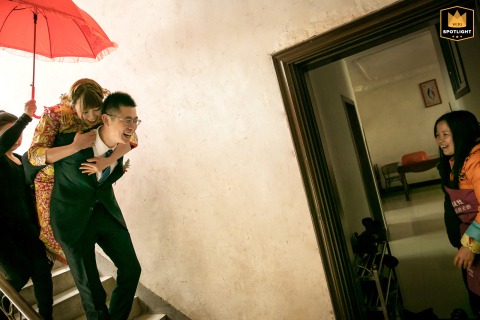 Shangyou, China — A wedding photojournalist captures a heartwarming scene as a groom escorts his bride to their ceremony, sharing joyful greetings with neighbors.