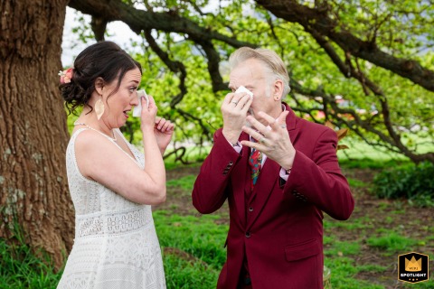 Documentary Photograph of A Melbourne Couple Wiping Away Tears Under A Tree A documentary photograph captures an emotional moment at a country property in Melbourne, Australia. The image shows the groom and bride wiping tears from their faces under a tree during their ceremony.