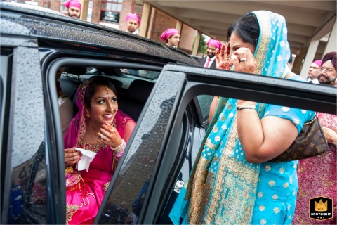 An Emotional Farewell: A Mother Cries Bidding Her Daughter Goodbye A documentary-style photograph captures an emotional moment at a Gurdwara in Surrey, England. The image shows the bride's mother crying while saying goodbye to her daughter after a Sikh wedding ceremony.