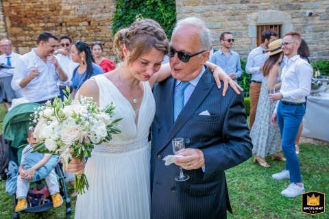 French Documentary: Father and Daughter Embrace at Montplaisir Wedding Estate A documentary style photograph taken at the Montplaisir estate in Condat sur Trincou, France, shows a father in the arms of his emotional daughter.