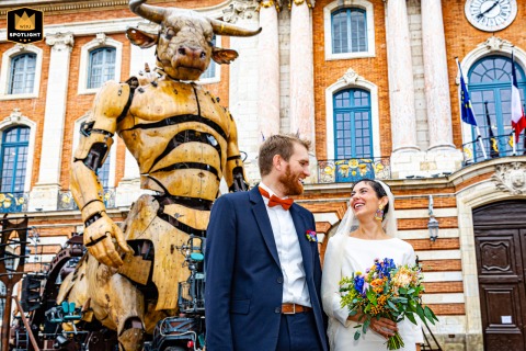 Toulouse's Minotaur Witnesses a Couple's Unforgettable Wedding Day Portrait At the Place du Capitole in Toulouse, a wedding photographer captures a unique moment. The newlyweds stand before a giant Minotaur statue, a powerful and singular portrait of their day.