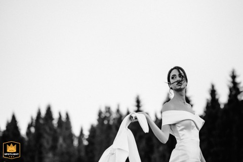 In the Ukrainian Mountains, a WPJA wedding photographer captures a dramatic, editorial-style bridal portrait. The black-and-white image focuses on the bride in her elegant satin gown, with a loose strand of hair blowing across her face.