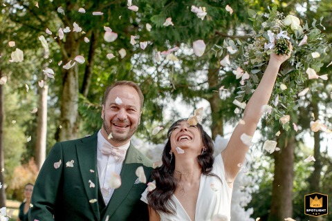 Joyous Bride And Groom Celebrate Under Petal Shower At Château De Fortis, France Château de Fortis, France: A joyous bride and groom celebrate amidst a shower of petals.
